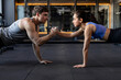 © Home-stock - Fit sportive man and woman doing plank core exercise in the gym, and standing on one hand, giving high five to each other, side view
