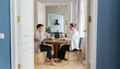 © muse studio - A barefoot man and woman, both in professional attire, work at a wooden table in a cozy, bright home.