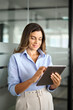 © insta_photos - Smiling mature professional business woman using tablet standing in office. Busy middle aged businesswoman manager, female executive leader holding pad digital tablet at work, looking at pad. Vertical