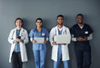 © peopleimages.com - Doctor, teamwork and technology on wall background for research, planning and multimedia workflow. Healthcare worker, group and nurse in portrait with laptop, tablet and phone for contact or about us