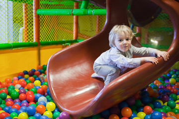 Toddler having fun in a green ball pit at the playground. Cute Kid Or Child Playing Colorful Balls on ball pit. toddler smiling