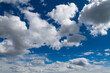 Clouds on a clear and sunny day with white cloud formations, hidden sun and deep blue sky. Wide angle shot on a day with nice weather in California.