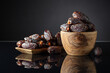Dates in wooden dish on a black background.