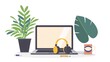 A laptop is on a desk with a plant and a cup