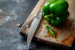 Green bell pepper closeup with a knife to it, over a wooden cutting board. Healthy food concept.