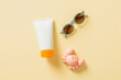 Flat lay composition with sunscreen tube mockup with sunglasses, and crab sand mold toy. Baby sun protection concept.