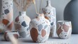 A terracotta vase with a modern twist featuring a terrazzo pattern in shades of grey white and blush pink..