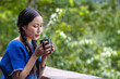 Portrait  of a beautiful asian woman wearing traditional  dresses pose holding and drinking hot coffee by sitting on balcony looking mountains and green nature is outdoor relaxed concept.