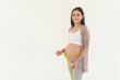 Pregnant woman using measuring tape to check size of belly pregnancy and baby development