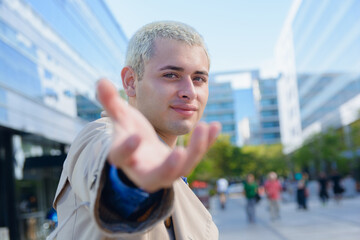 Wall Mural - young gay man outdoors handsome short hair shakes his hand inviting you to walk with him