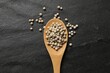 Aromatic spice. White pepper in spoon on black table, top view