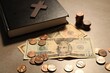 Donate and give concept. Coins, Bible, cross and dollar banknotes on grey table