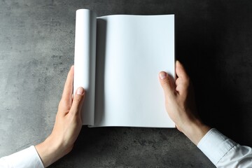 Canvas Print - Man holding blank notebook at black textured table, top view. Mockup for design