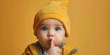 Fototapeta  - Adorable Baby Boy Making Shushing Gesture with Finger on Lips Keeping a Secretive Curious Expression on Vibrant Orange Background