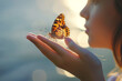 Gentle serene image capturing a close-up of a woman with a painted lady butterfly resting on her hand against a blurred, glowing sunset background