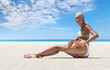 woman on the hot summer beach applying sunscreen lotion to buttocks skin for care and sun protection, in sunny sea day with blue sky. Concept for online shopping, tanning during summer travel holiday