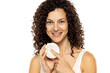 Portrait of an attractive young woman holding a beauty product against a white background.