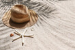 Summer vibes. Broad brim straw hat and sunglasses on a sandy beach. Copy space for text.