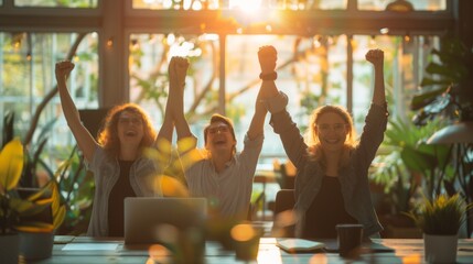 Business team celebrating a victory with raised arms in a modern workplace at sunset