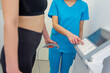 A woman undergoes a body composition analysis with a professional health expert