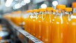 Line of bottling of orange fruit juice bottles on clean light factory with closeup view on the sweet drink bottle
