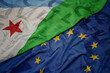 waving colorful flag of european union and flag of djibouti on a euro money banknotes background. finance concept.