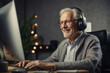 An old man is sitting at a computer. Smiling.He communicates via the Internet.