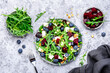 Delicious salad with sweet beets, blueberries, feta cheese, arugula and walnuts, gray table background, top view