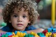 © Anastasiia - Young child with curly hair plays with colorful building blocks. Concept Kids Playing, Curly Hair, Building Blocks, Colorful Props, Joyful Expressions