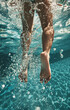 Cropped image of female legs in swimming pool with water splashes