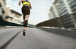 Sporty young woman running on street, low angle view. Motion blur effect showing her speed