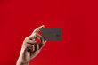 Close up hand holding credit card isolated red background.