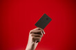 Close up hand holding credit card isolated red background.