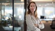 © Cassova - A poised woman in casual business attire stands confidently in a well-lit office environment.