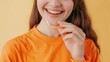 © liliyabatyrova - A woman is smiling and holding a clear plastic retainer in her hand