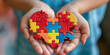Cupped hands presenting a colorful heartshaped puzzle symbolizing love support and autism awareness