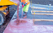 Parts of builder pouring and leveling color wet ready-mix concrete into formwork  during new footpath construction