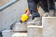 Concrete steps under construction as team of builders install heavy concrete blocks. Feet and hands of workers. 