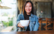 Blurred image of a woman holding and serving a cup of hot coffee in cafe