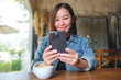 Portrait image of a young woman holding and using mobile phone in cafe