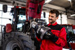 Professional mechanic servicing tractor transmission inside workshop.