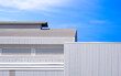 Aluminium steel wall with louver and gable roof of factory and warehouse building against blue sky background