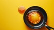 A glossy pancake lavishly coated in syrup lies in a frying pan the glossy texture highlighted by a bright yellow backdrop
