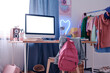 No people shot of computer with blank screen on table and clothes rack in modern teen students room interior, copy space