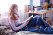Modern Caucasian girl wearing casual clothes relaxing on bed in her bedroom reading notes in notebook, copy space