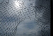 Looking up at a chain link fence with blue sky and clouds. wire fence. Chain link fence see blue sky. Opening in metallic fence. blue sky. Challenge. breakthrough concept. metaphor. Chain-link, wire