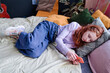 High angle view of Caucasian teen girl lying on bed in her bedroom holding smartphone waiting for message or phone call