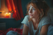 Chica 30s expresión angustiada, sentada en la cama detalles en rojo, pensado en su situación económica o cara de insomnio, pijama gris, depresión, ayuda psicológica