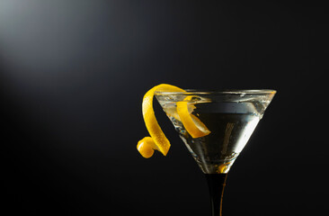 Wall Mural - Glass of classic dry martini cocktail with green olives on a black background.