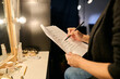 Close up of unrecognizable actress reading script backstage and taking notes copy space